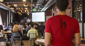 Employee watches a presentation from back of room